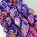 Multicolored yarn skeins with purple, blue, and pink hues on a light background